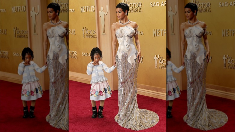 Teyana Taylor wearing a figure-hugging dress while holding the hand of her young daughter Rue Rose Shumpert