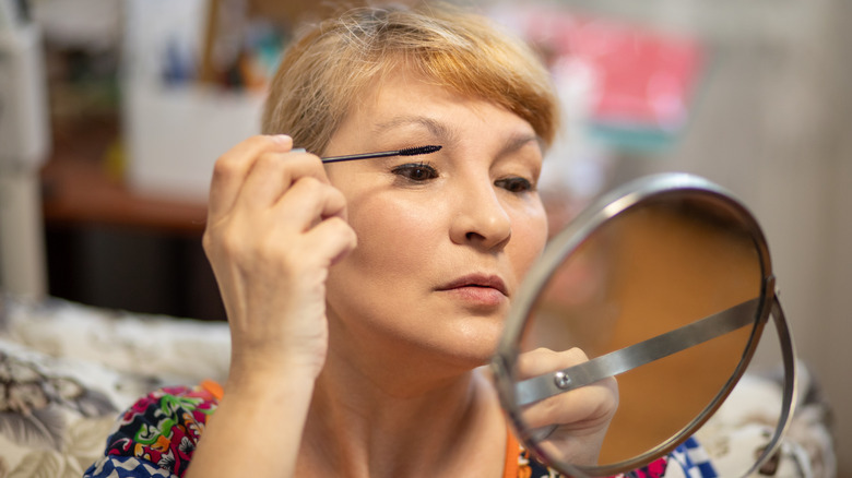 An older woman applying mascara