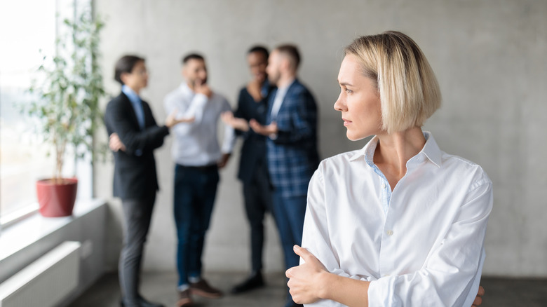 Woman looks over at group of men speaking