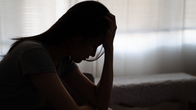 woman holds head in hands