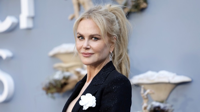Nicole Kidman posing on the red carpet in a black blazer with a white flower accessory