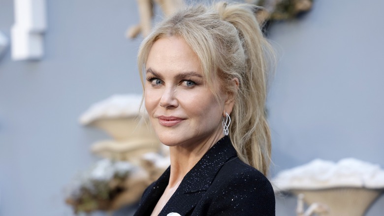 Nicole Kidman wearing a black blazer and slightly smiling on the red carpet with her hair in a ponytail