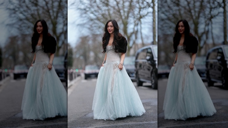 A woman in a light blue sheer dress with a black fur bolo, on a city street
