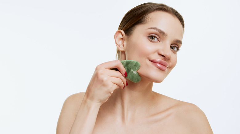 Woman giving herself a massage with gua sha