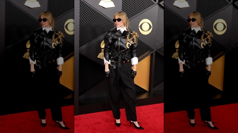 Miley Cyrus wearing a black leather jacket, tailored trousers, and black slingback heels
