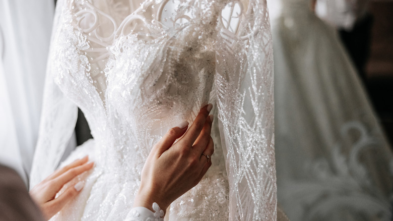 A close-up of a woman's hands touching a wedding dress