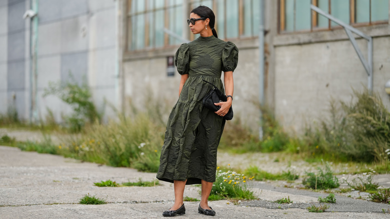 A woman in a green dress and black flats outside
