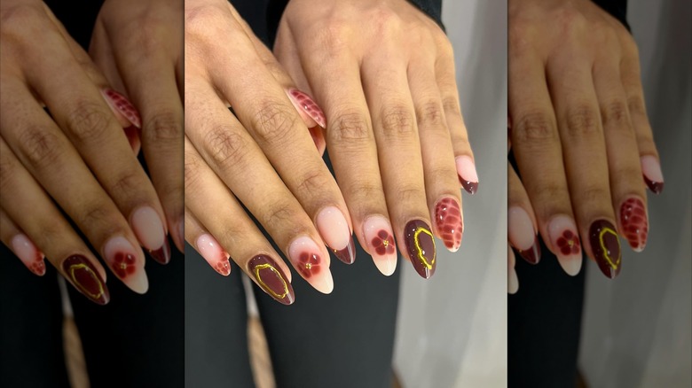 Two side-by-side hands showing nails with a crocodile, blooming flower, and gold-accented nails