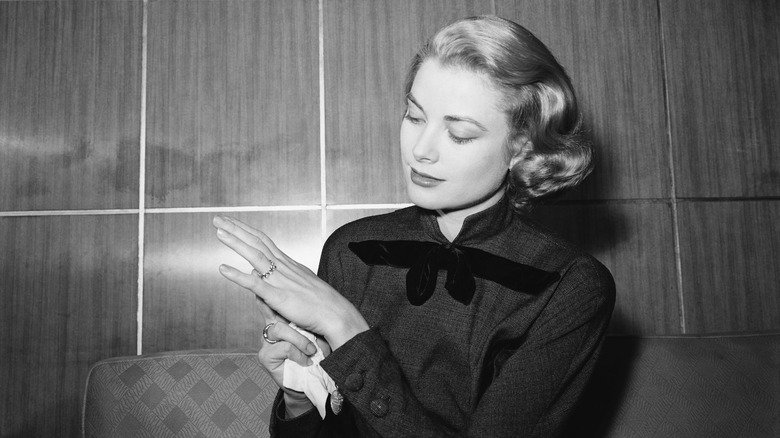 Grace Kelly looking down at her ringed hand while wearing Old Hollywood curls