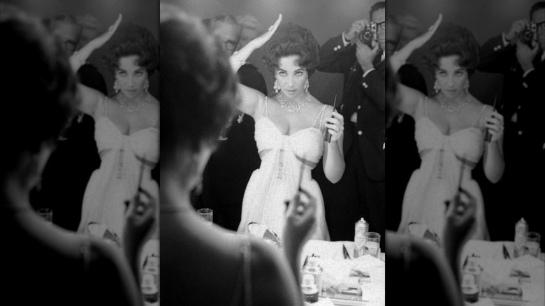 Elizabeth Taylor adjusting her hair in front of a mirror in 1959