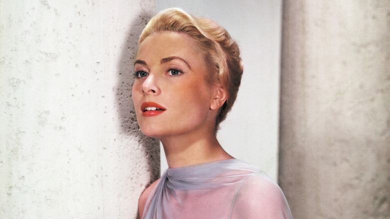 Grace Kelly in a blue dress leaning against a pillar