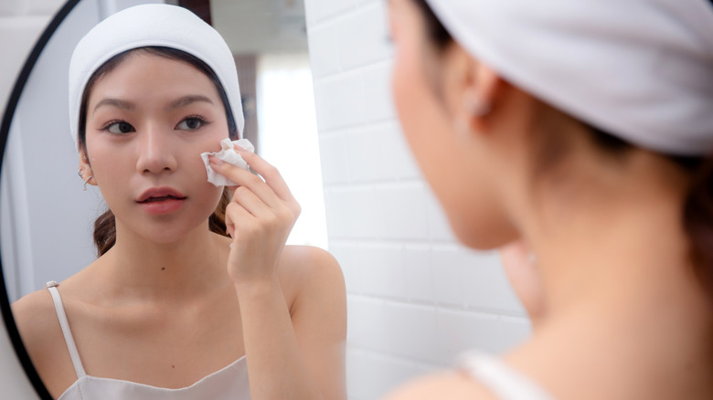 A woman removing her makeup in the mirror
