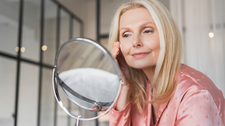 A mature woman applying moisturizer to her face