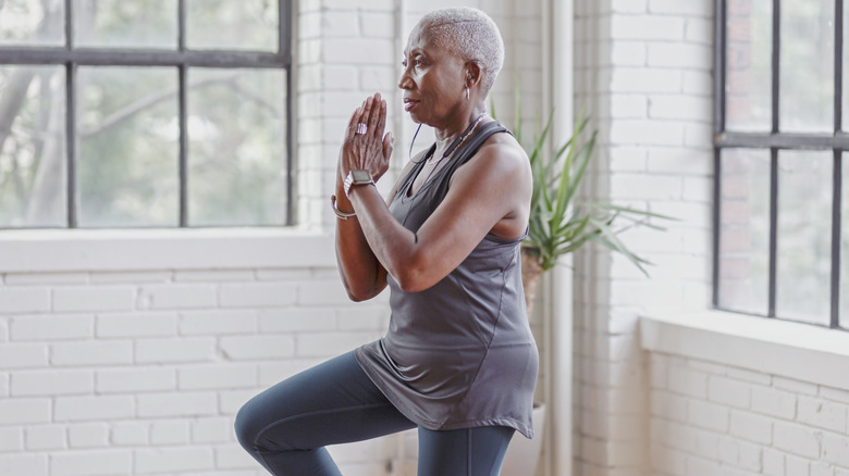 An older woman doing tree yoga pose