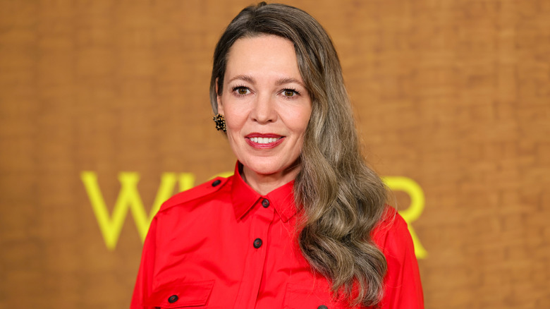 Olivia Colman on the red carpet with a red shirt and long gray hair