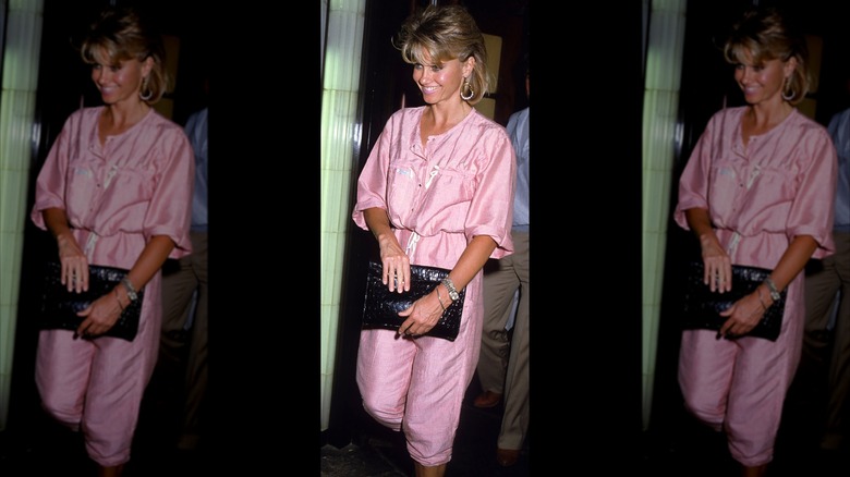 Olivia Newton-John smiling in a pink jumpsuit in 1979