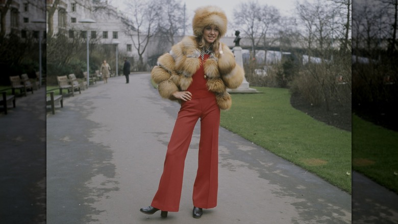 Olivia Newton-John posing in London around 1970 in a red ensemble with a fur-look hat and jacket