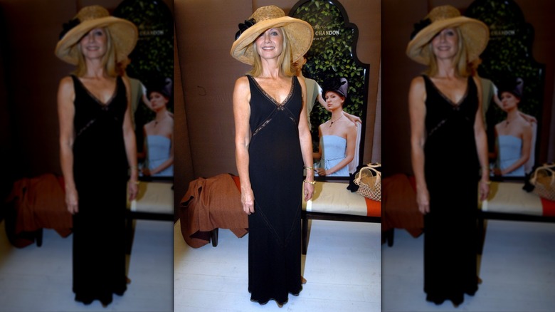 Olivia Newton-John wearing a long, black dress and a large-brimmed hat in 2002