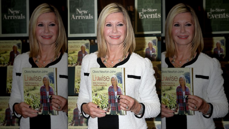 Olivia Newton-John holding a copy of her recipe book in 2012