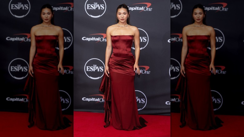 Chloe Kim posing on the ESPYs red carpet wearing a deep red gown with a strapless bodice