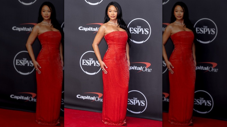 Suni Lee posing with a hand loosely on her hip while wearing a bright red gown