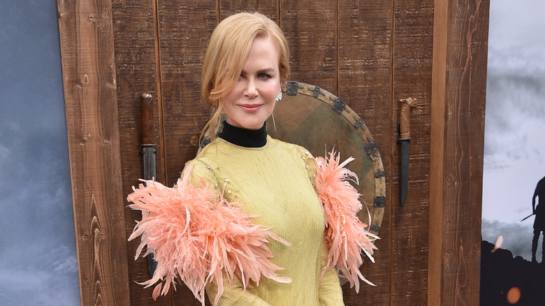 Nicole Kidman on the red carpet in a yellow dress embellished with pink feathers