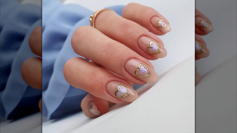 Half-folded hand showing a heart-shaped nail design featuring an opal effect