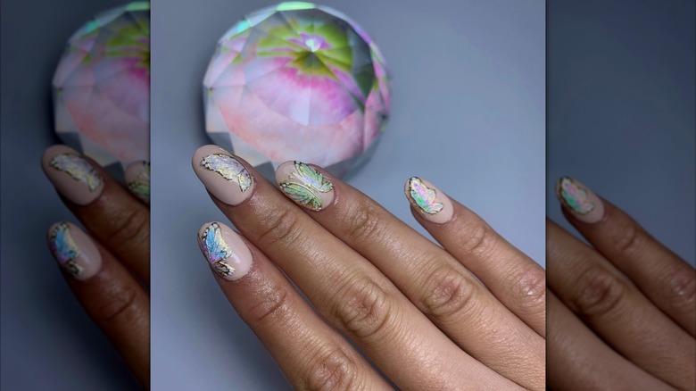 Hand showing an opal-colored butterly nail design