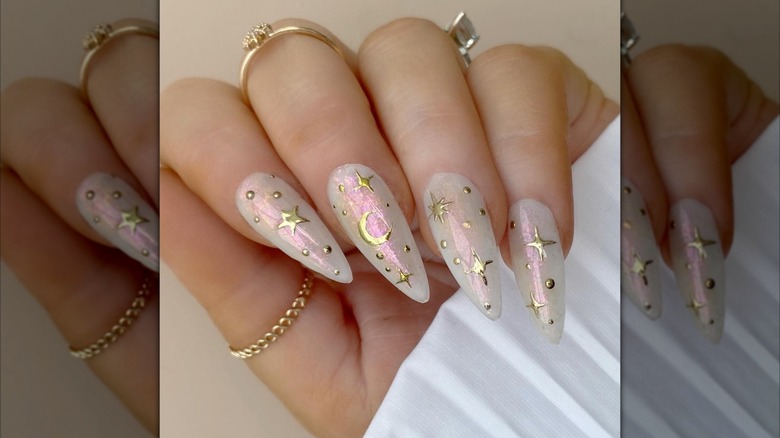 Folded hand with nails featuring gold star designs over an opal background