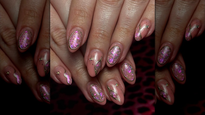 Two hands showing off a pink-toned, geode-inspired set of nails