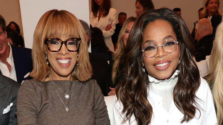 Oprah Winfrey in white and Gayle King in brown seated together at an event