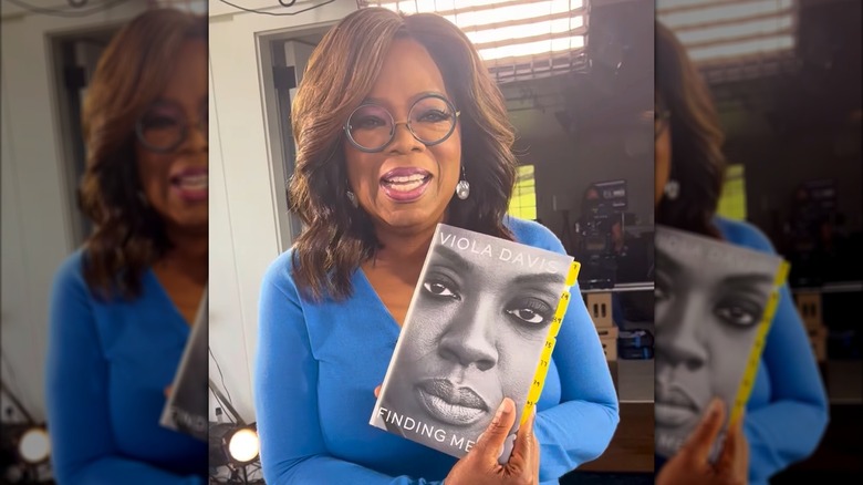 Oprah Winfrey holding a copy of Finding Me by Viola Davis