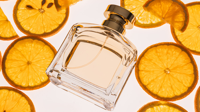 Perfume bottle lying down surrounded by sliced orange peels