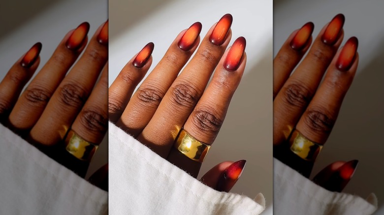 Open hand showing nails with an aura effect featuring shades of brown and orange