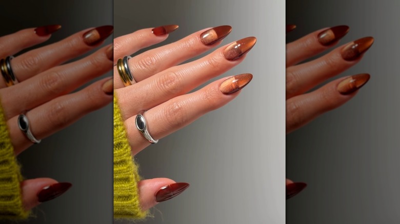 Open hand showing nails with a brownish orange nail polish and cat eye effect
