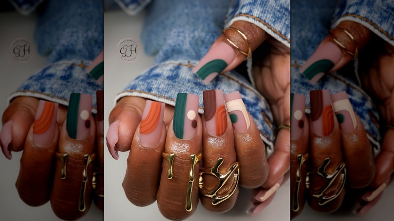 Two hands showing an abstract nail design featuring muted fall colors