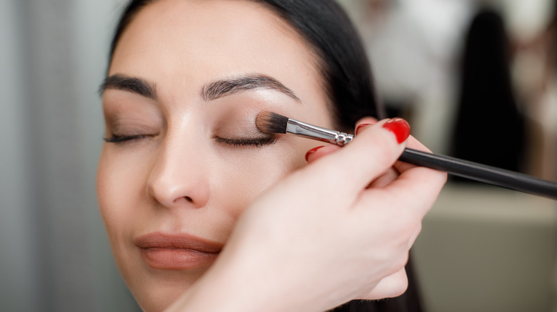 Application of cream eyeshadow on woman