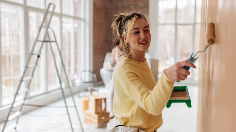 A young woman is painting a wall