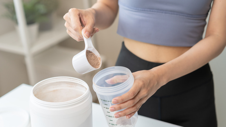 A woman puts a spoonful of powder into a shaker