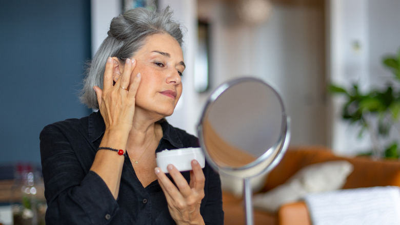 Woman applying moisturizer to face