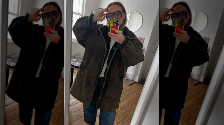 A woman talking a mirror selfie in a heavy coat with dark brown shearling lining