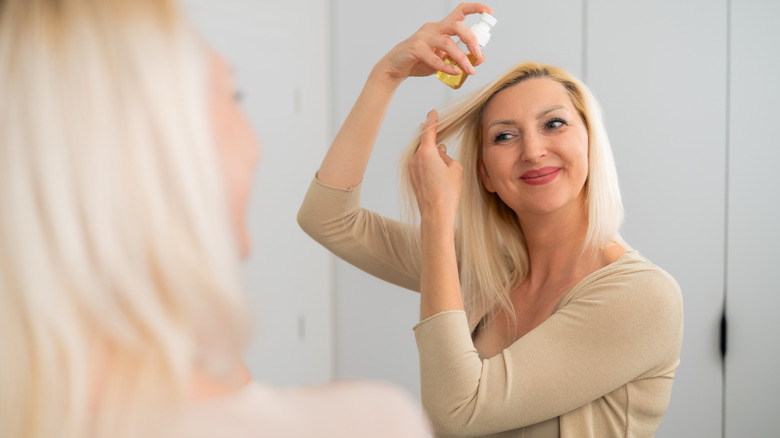 Woman spraying product onto her hair