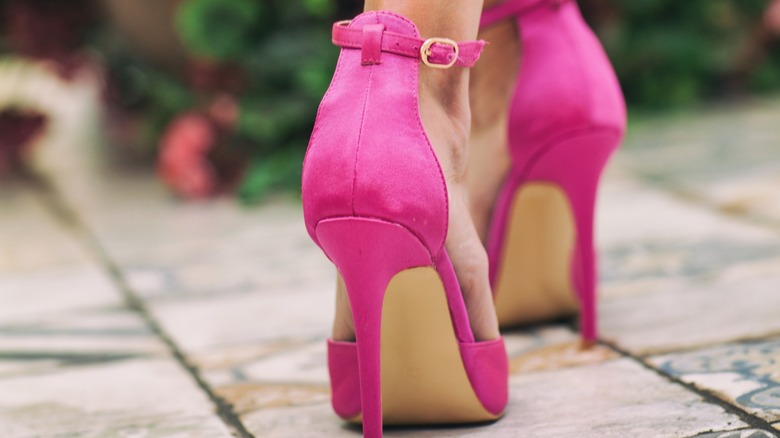 A person wearing pink stiletto heels