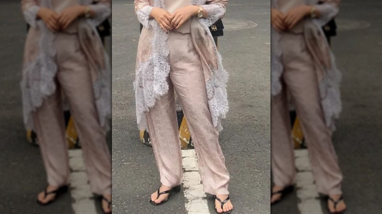 Bottom half of a woman's loose, silky outfit with black thong sandals