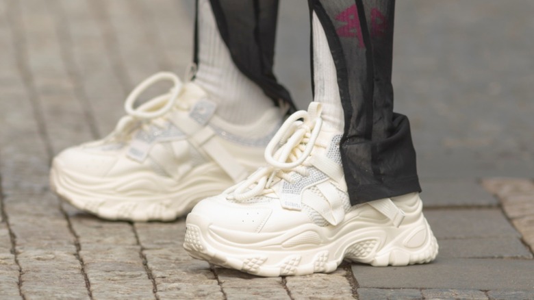 A person wearing chunky, white sneakers