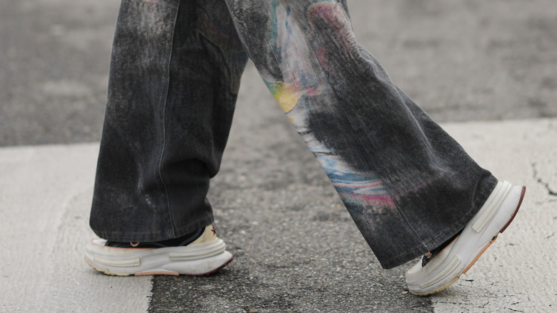 A close up of a woman wearing black jeans with thick, chunky sneakers