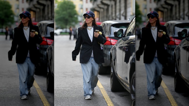 Woman photographed in ultra baggy clothes, sunglasses, and a baseball cap