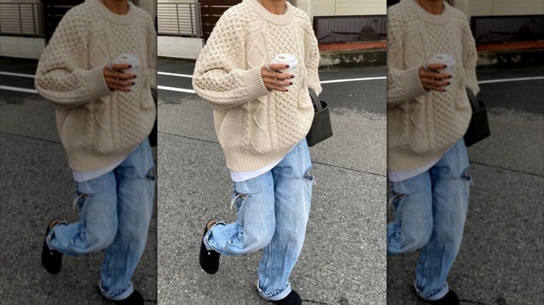 A woman walking down the street in slouchy jeans and an oversized sweater