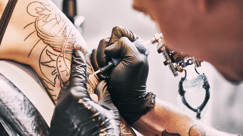 Tattoo artist working on a tattoo on a person's arm