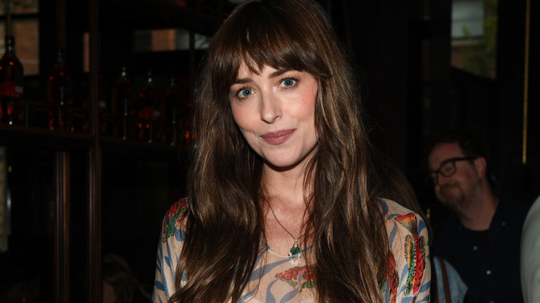 Dakota Johnson at a premiere wearing a gown with fish on it